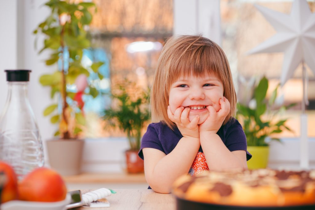 little girl smiling and looking at food